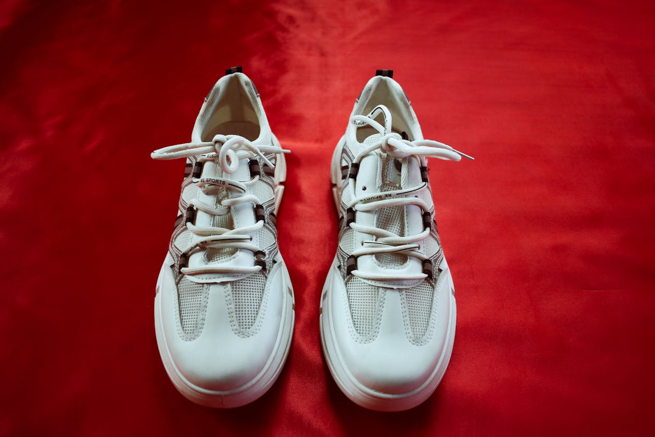 Top view of fashionable white sneakers on a bold red background, perfect for footwear fashion and design.